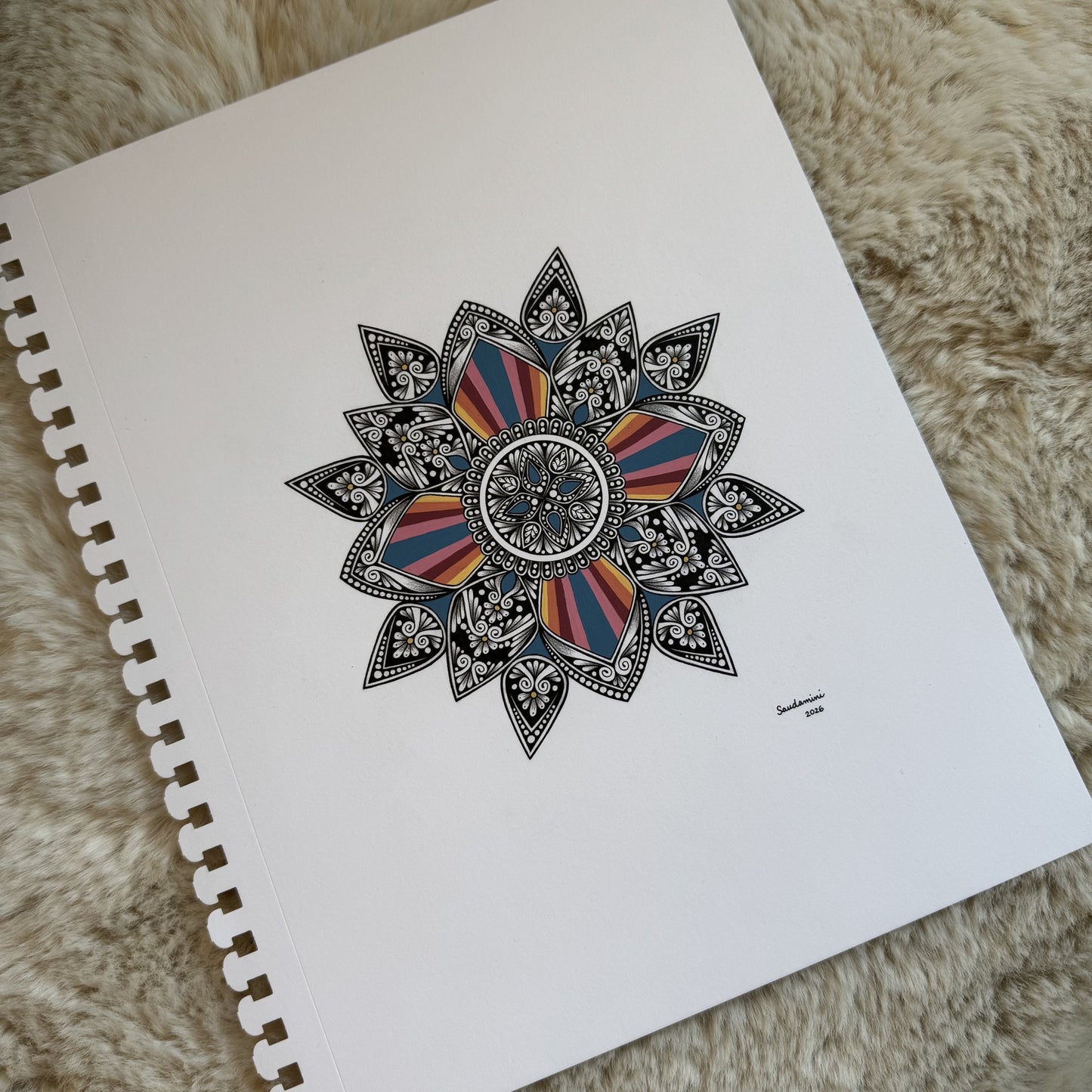 Hand-drawn colorful mandala by Saudamini Madra in ink on Bristol paper, detail view on textured surface