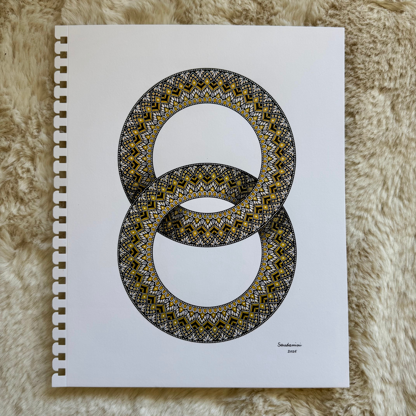 Zentangle design within two interlocking rings artwork resting on a textured surface