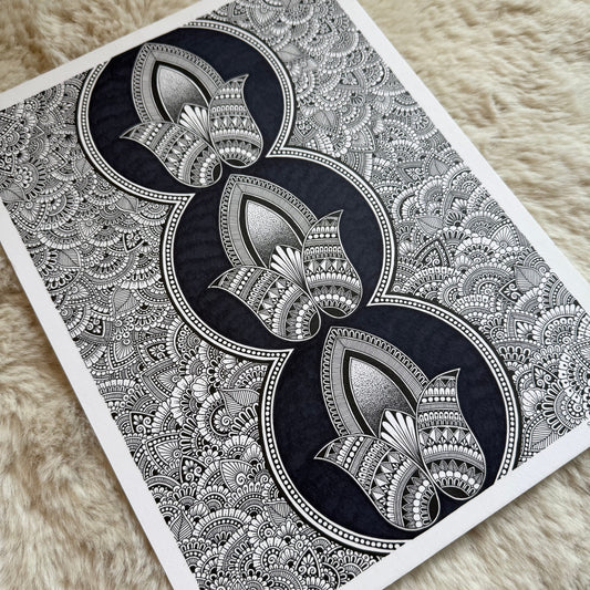 Hand-drawn zentangle by Saudamini Madra showing three lotus forms in black ink on Bristol paper, photographed on textured surface