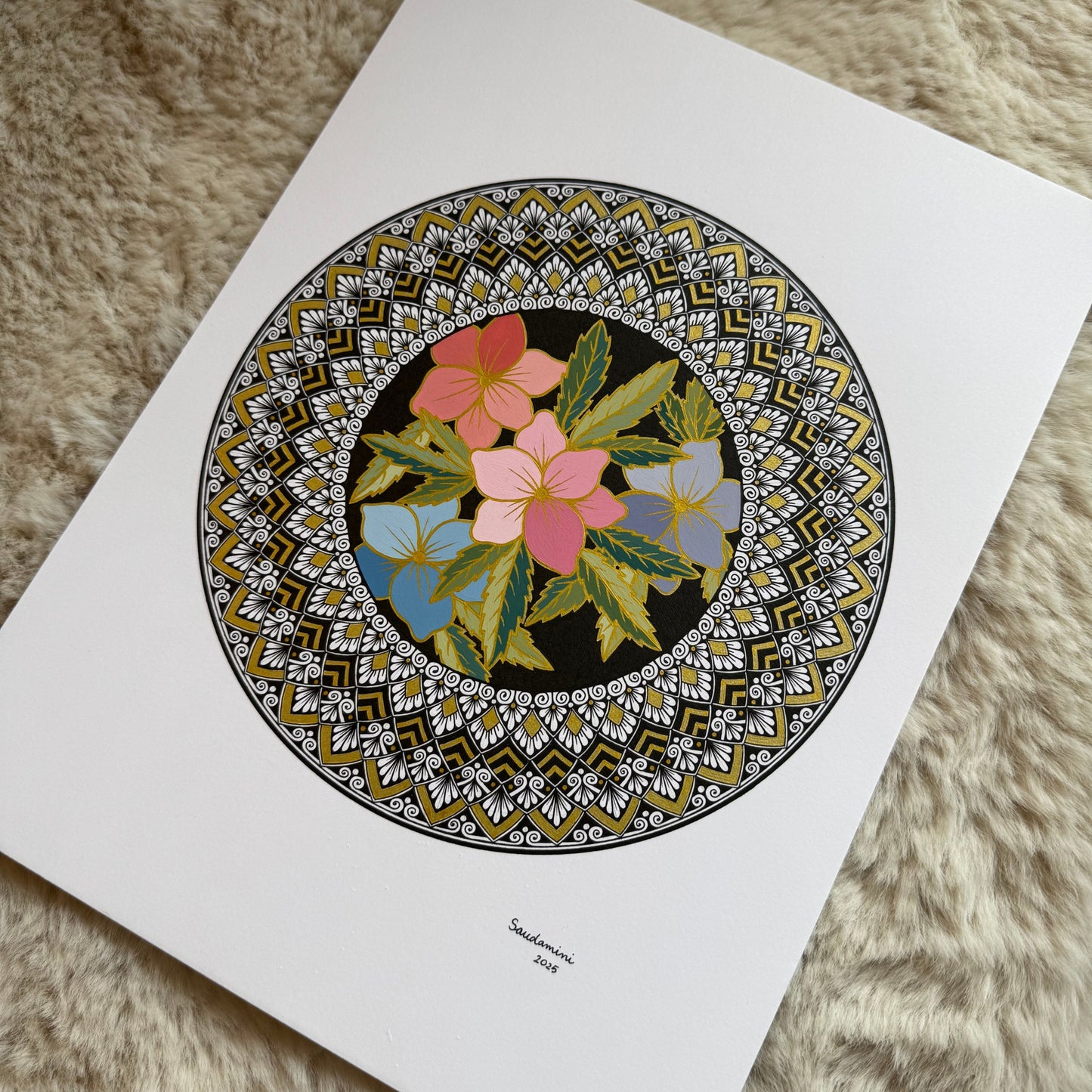 Hand-drawn mandala by Saudamini Madra with pink and blue flowers in ink and color on Bristol paper, photographed on textured surface