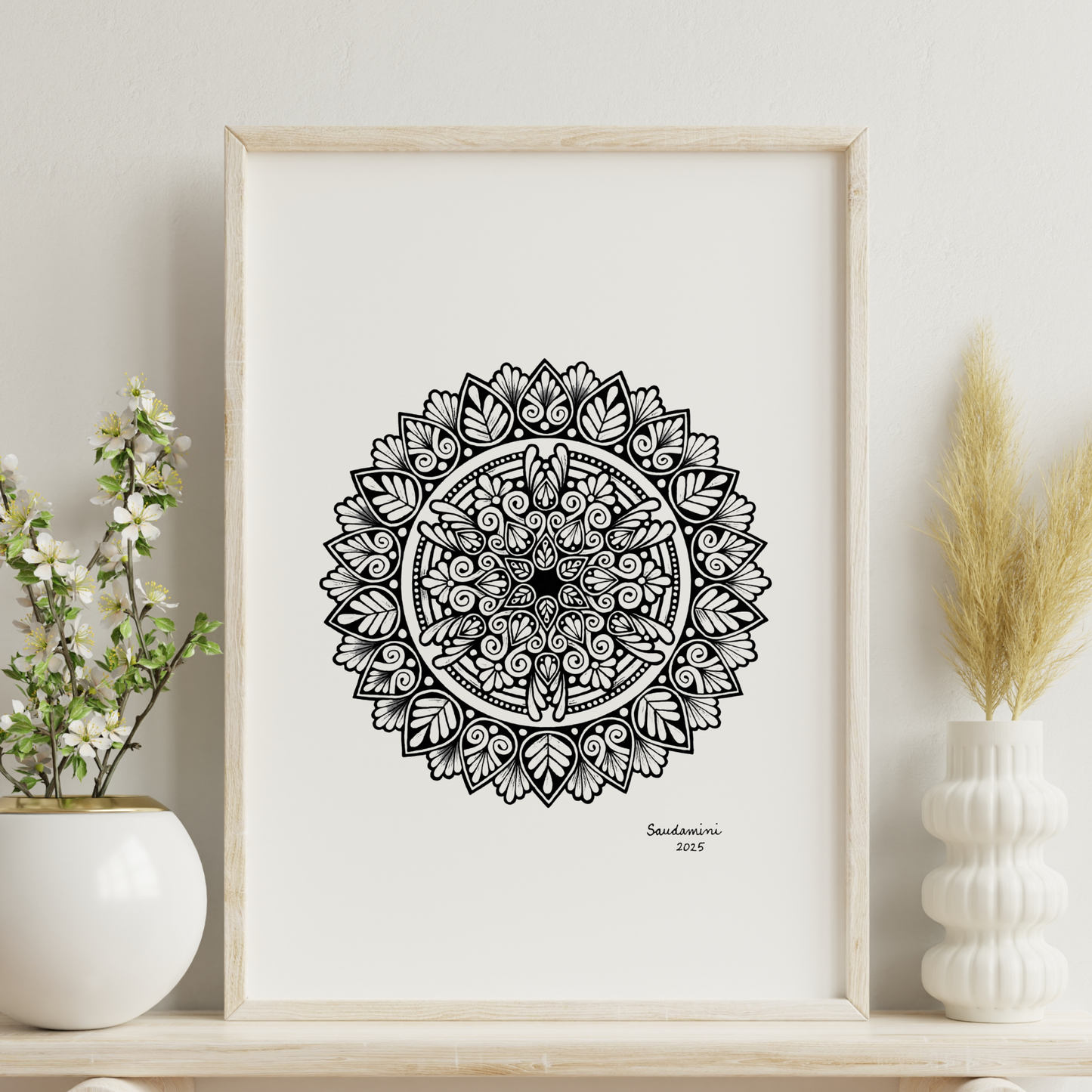 Black mandala artwork on a white wall with decorative plants.