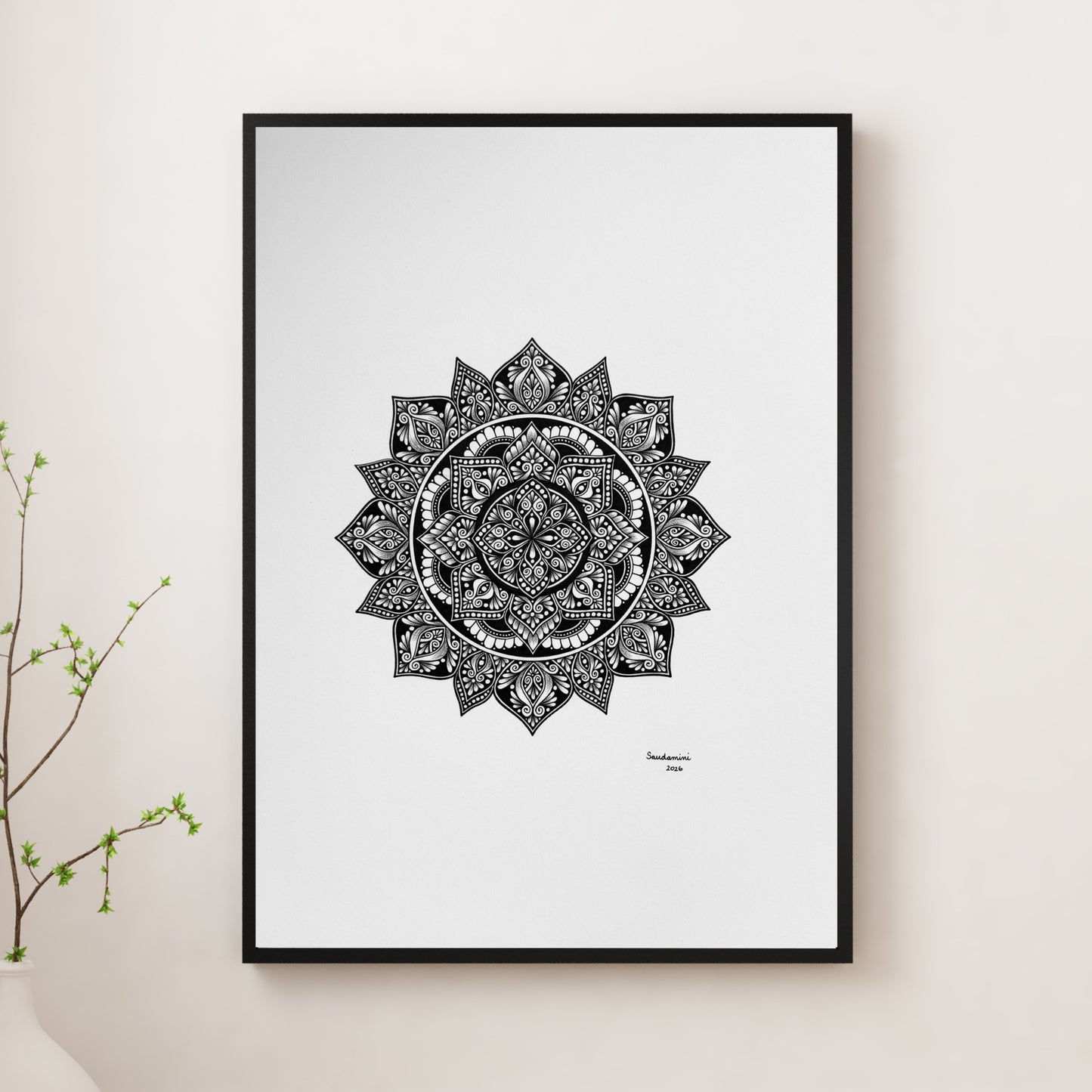 Composite mockup of Petals for an Unspoken Wish Mandala by Saudamini Madra, a circular mandala in black ink on Bristol paper, shown in a black frame on a white wall