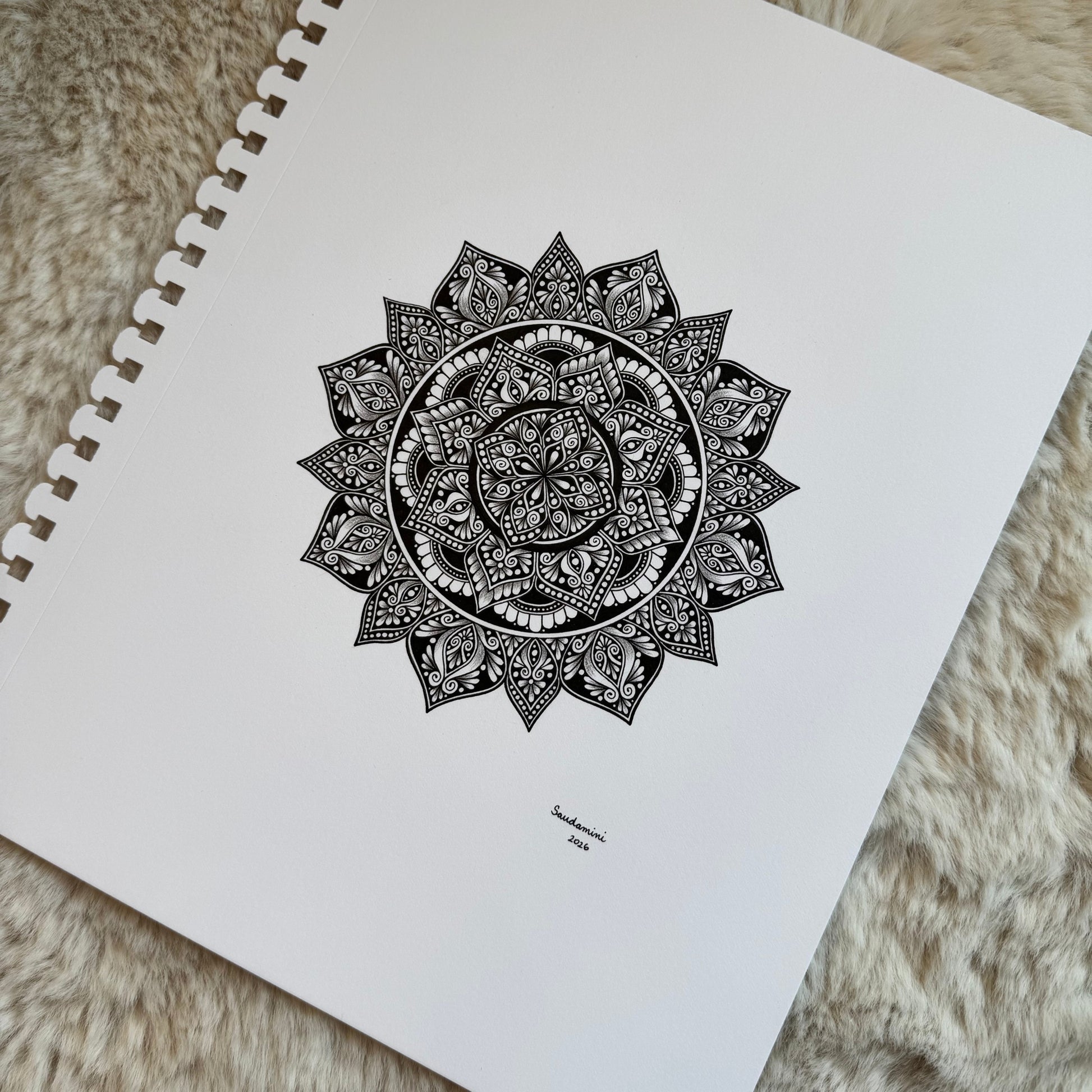 Hand-drawn mandala by Saudamini Madra in black ink on Bristol paper, detail view on textured surface