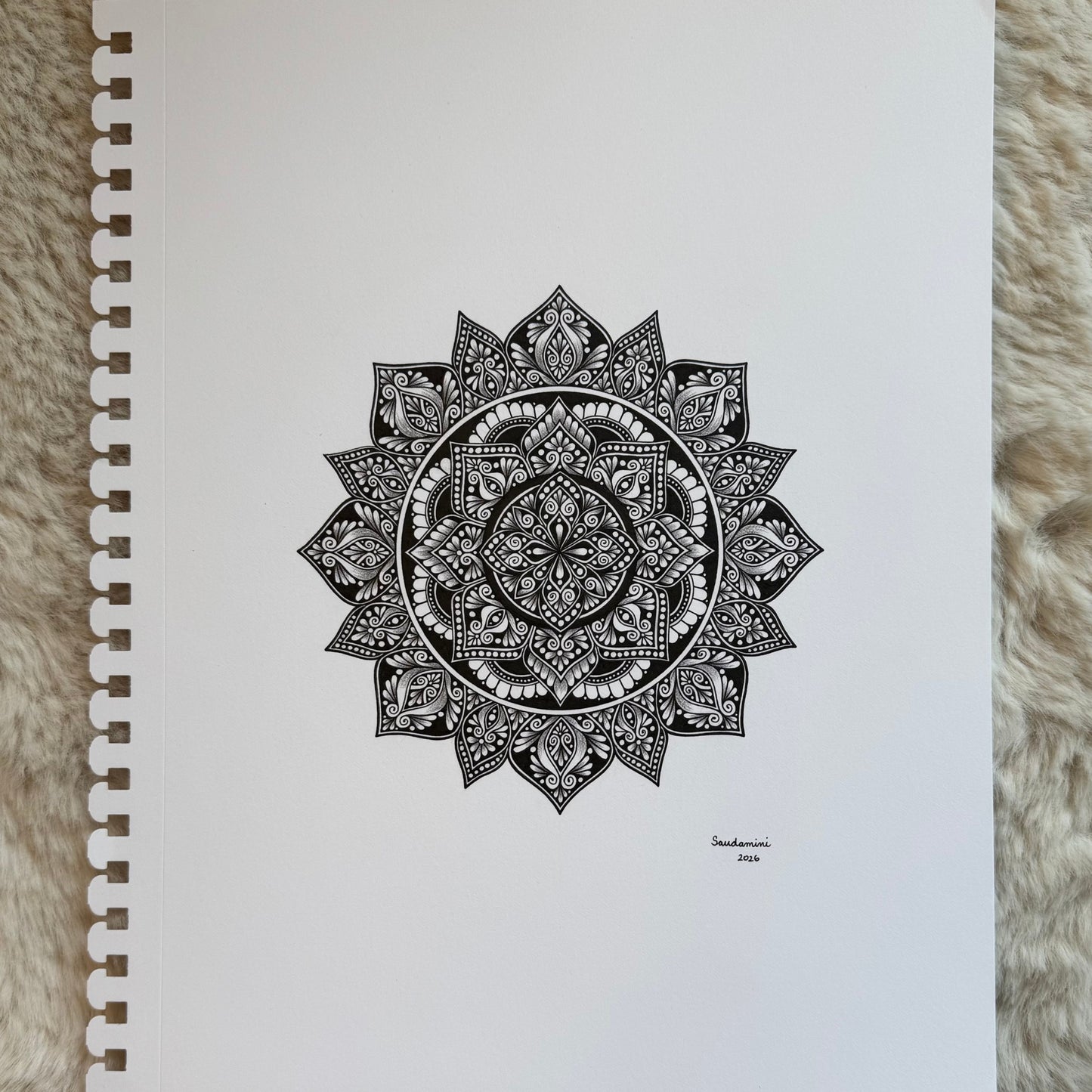 Hand-drawn mandala artwork by Saudamini Madra showing fine geometric patterning in black ink on Bristol paper