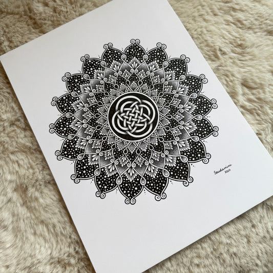 Hand-drawn mandala by Saudamini Madra with interlaced knot center in black ink on Bristol paper, photographed on textured surface