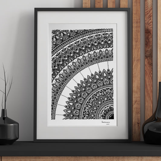 Composite mockup of The Memory of a Whole Mandala by Saudamini Madra, a cropped mandala arc in black ink on Bristol paper, shown framed against a wood-paneled wall