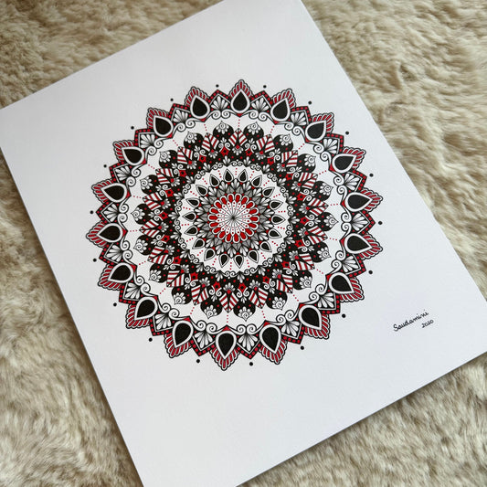 Hand-drawn mandala by Saudamini Madra in black and red ink on Bristol paper, photographed on textured surface