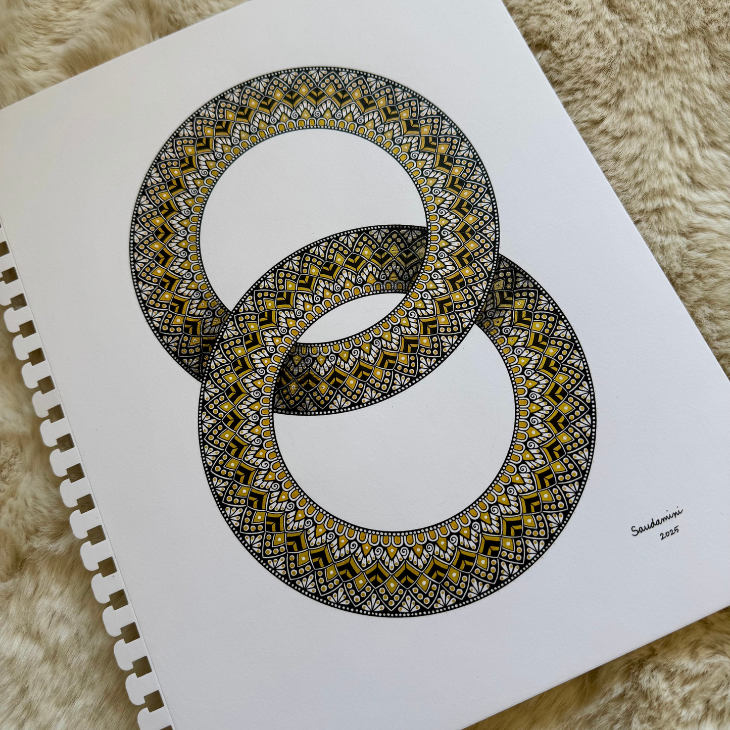 Zentangle design within two interlocking rings artwork resting on a textured surface