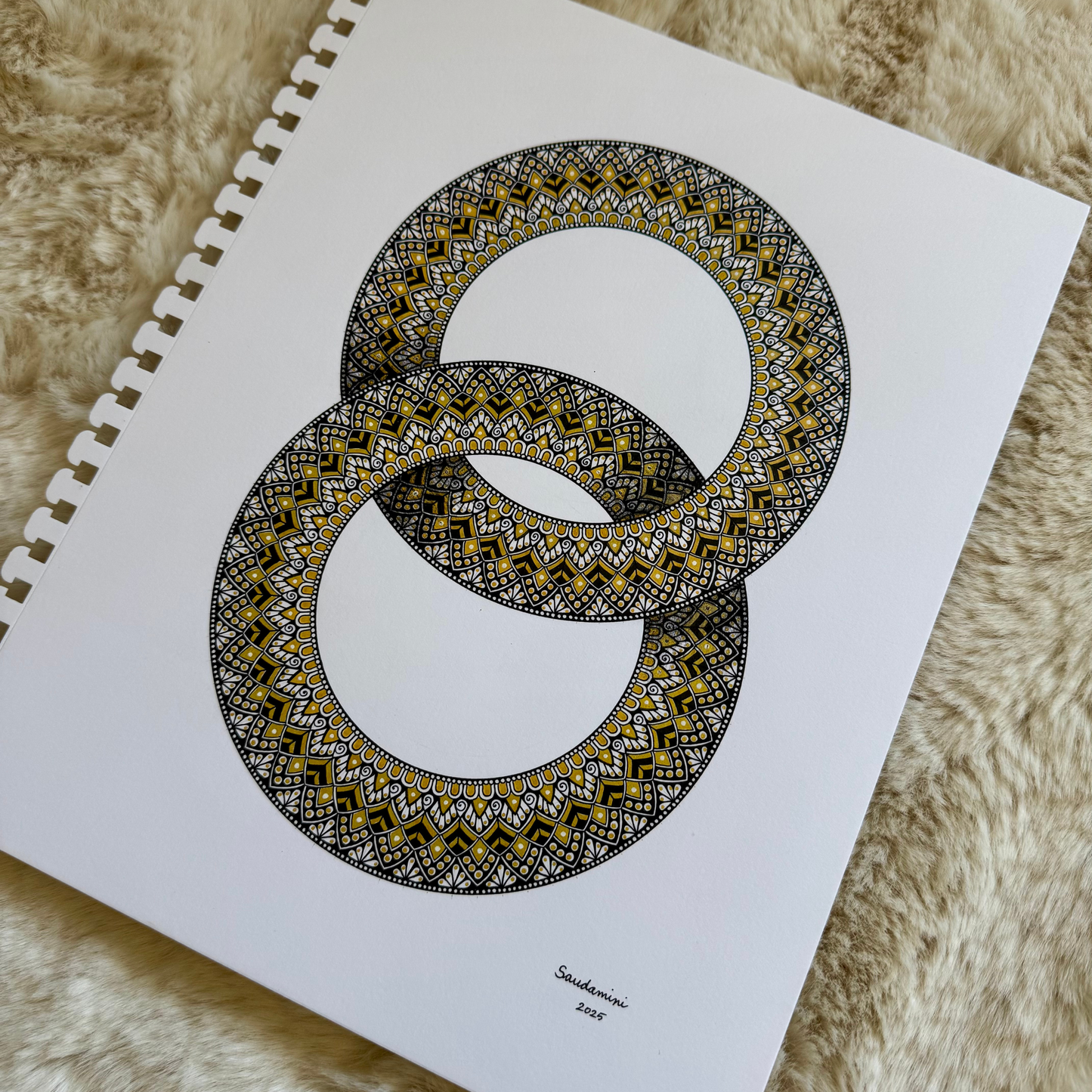 Zentangle design within two interlocking rings artwork resting on a textured surface