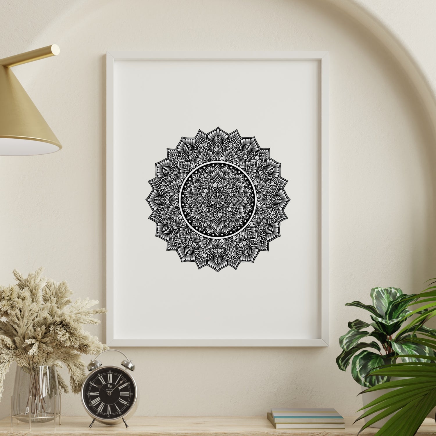 Composite mockup of Where Time Softens Mandala by Saudamini Madra, a dense circular mandala with open white center in black ink on Bristol paper, shown in a white frame on a warm wall