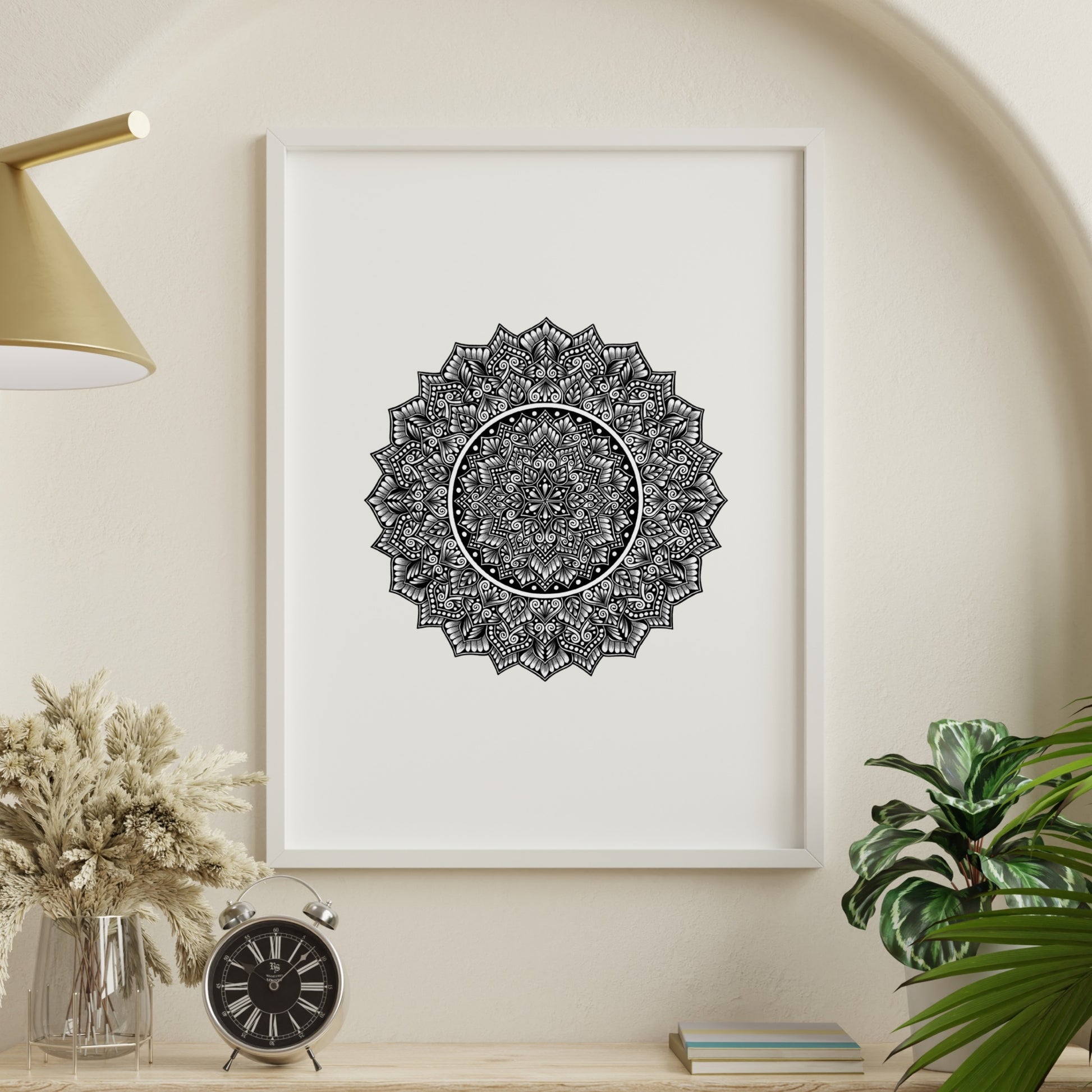 Composite mockup of Where Time Softens Mandala by Saudamini Madra, a dense circular mandala with open white center in black ink on Bristol paper, shown in a white frame on a warm wall