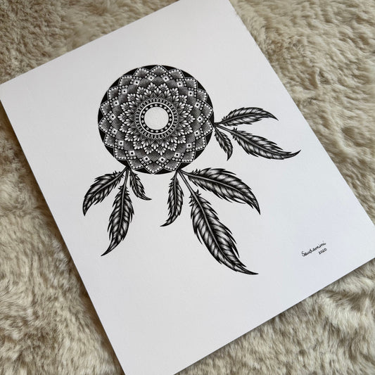 Hand-drawn dreamcatcher mandala by Saudamini Madra in black ink on Bristol paper, circular mandala form with seven hanging feathers, photographed on textured surface