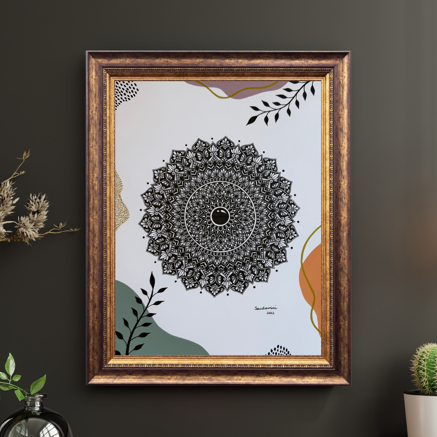 Framed mandala art on a dark wall with decorative elements.